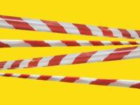 Red and white warning lines of barrier tape prohibit passage